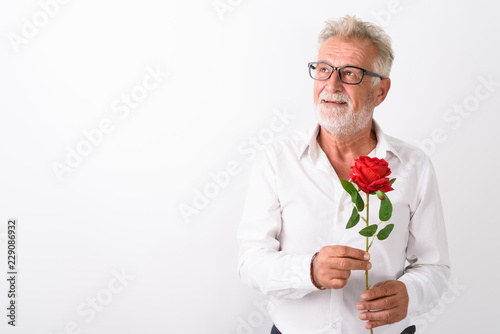 Studio shot of happy senior bearded man smiling while thinking a