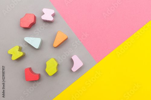 Flat lay, top view. colorful geometric details of a pyramid, sorter on graphic gray-pink-yellow background with a place for the text. children's educational wooden toys