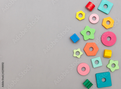 children's wooden toys, colorful geometric details of a pyramid sorter on a gray background with space for text. Flat lay, top view