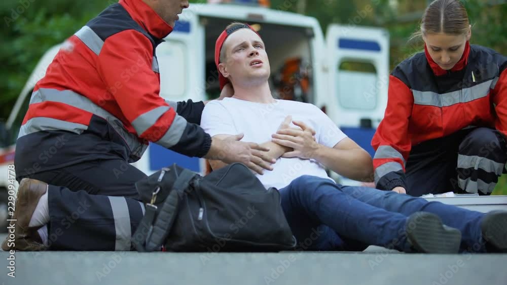 Paramedics caring for man suffering from chest pain, qualified medical care Paramedics caring for man suffering from chest pain, qualified medical care
