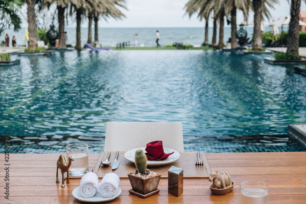 Obraz premium Table And Chair with Blur Swimming Pool Of The Background. Summer Vacation concept 