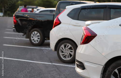 Closeup of rear side of white car park in parking area in the evening. 