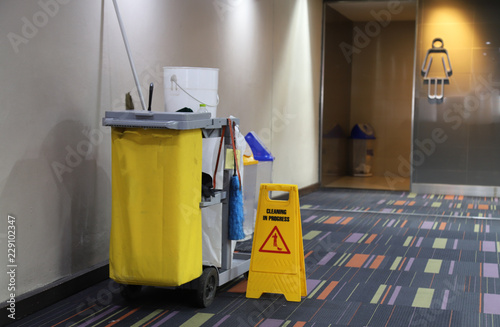 Closeup of cleaning equipment and tools for floor cleaning in front of woman WC.