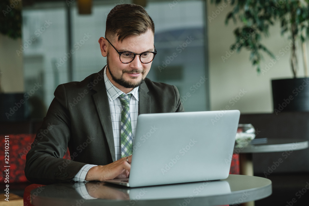 Young successful businessman working on a laptop while sitting in cafe. Young successful businessman working on a laptop while sitting in cafe.