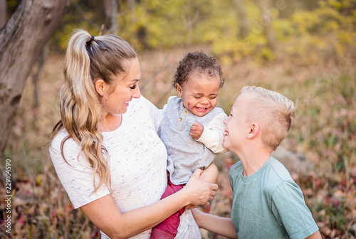 Beautiful candid portrait of a mother playing with her cute children. Mother and her two boys spending time together in the outdoors and laughing together. Great adoption or blended family photo photo