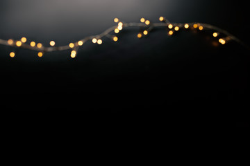 Abstract christmas lights on  black  background. Defocused  Glowing light bulb garland, copyspace