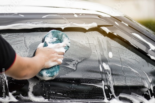 Use your right hand to catch the sponge and polish the car window. Concept car wash.