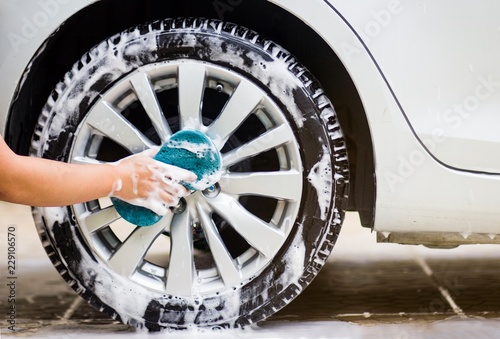 This image is a picture of wiping the car with a blue microfiber cloth by hands.Car wash concept.