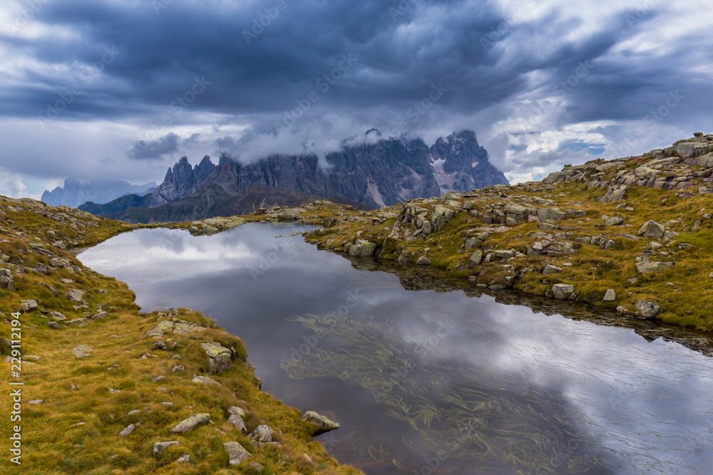 Clouds and mountain peaks reflection in the Dolomite Alps