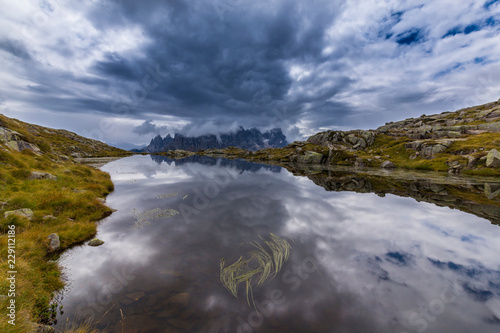 Clouds and mountain peaks reflection in the Dolomite Alps