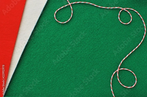 Christmas crafts from felt fabric background with red, green and white felt and decorative rope.