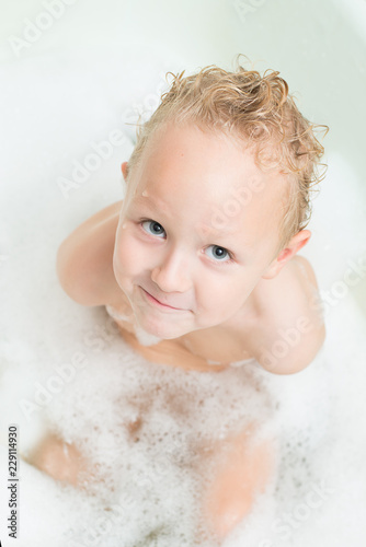 Happy baby bathes in the bathroom with foam