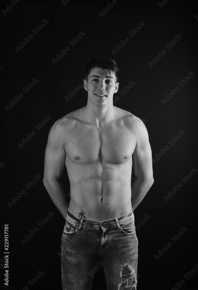 portrait of young man with  torso naked with jeans on black background
