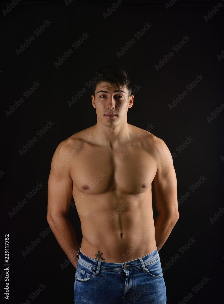 portrait of young man with  torso naked with jeans on black background