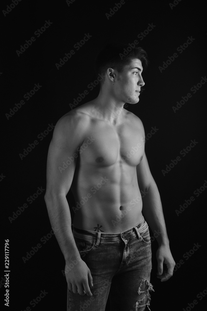 Fototapeta premium portrait of young man with torso naked with jeans on black background