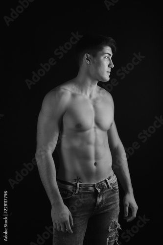 portrait of young man with torso naked with jeans on black background