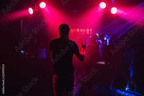 mc with microphone on the night club scene on the background of blurred dancing people