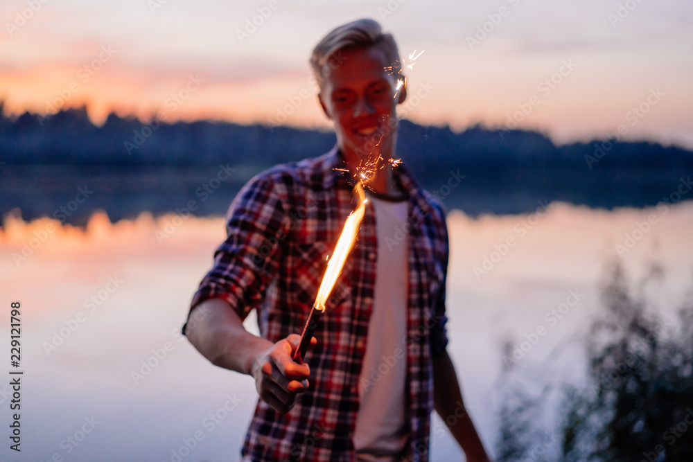 Young man with sparkler in his hand