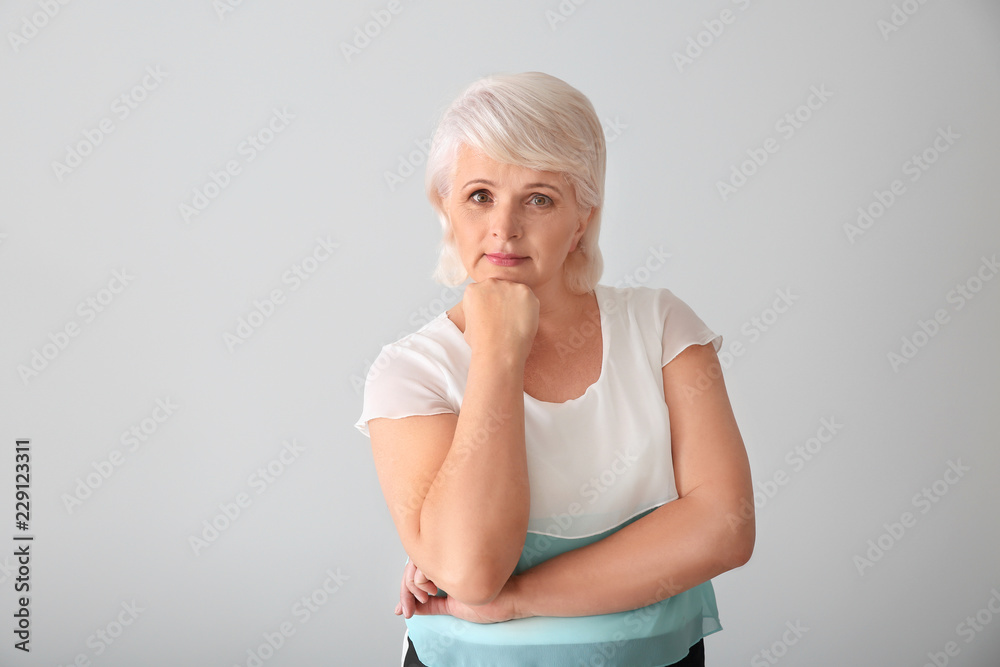 Portrait of thoughtful mature woman on light background Portrait of thoughtful mature woman on light background
