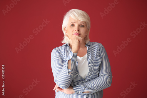 Portrait of thoughtful mature woman on color background