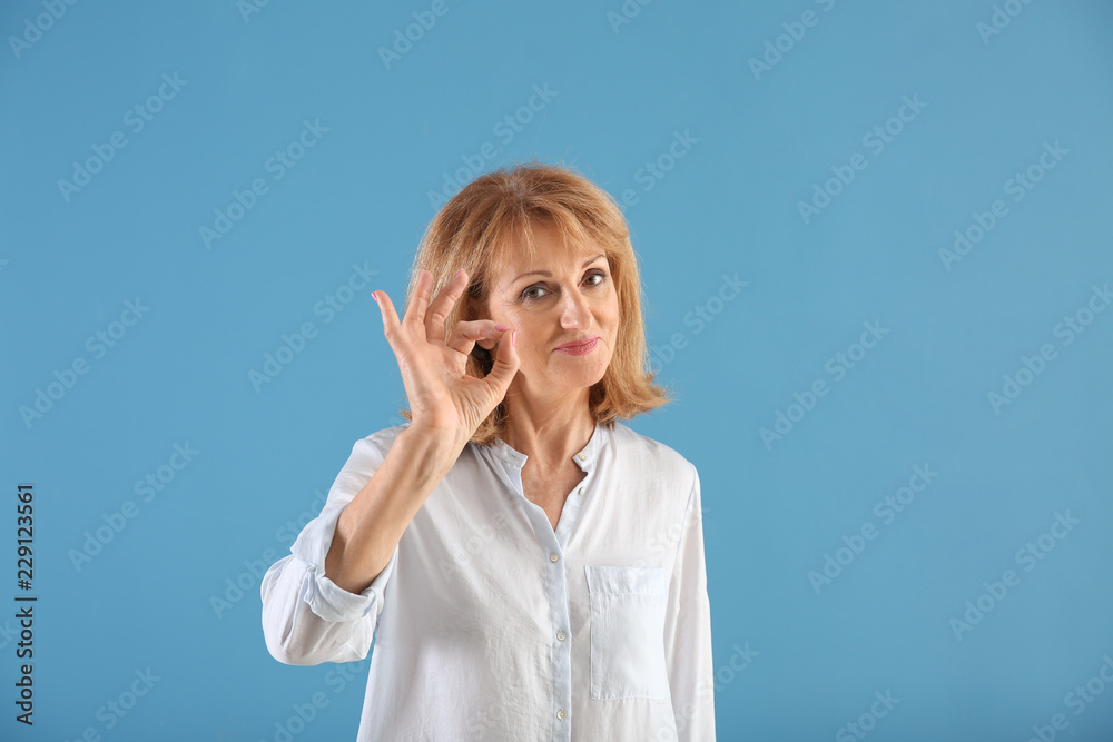 Portrait of mature woman showing OK gesture on color background Portrait of mature woman showing OK gesture on color background