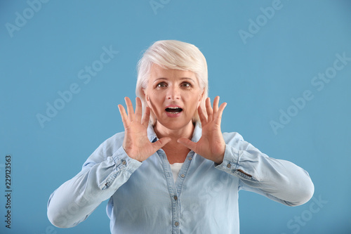 Portrait of mature woman calling for someone on color background