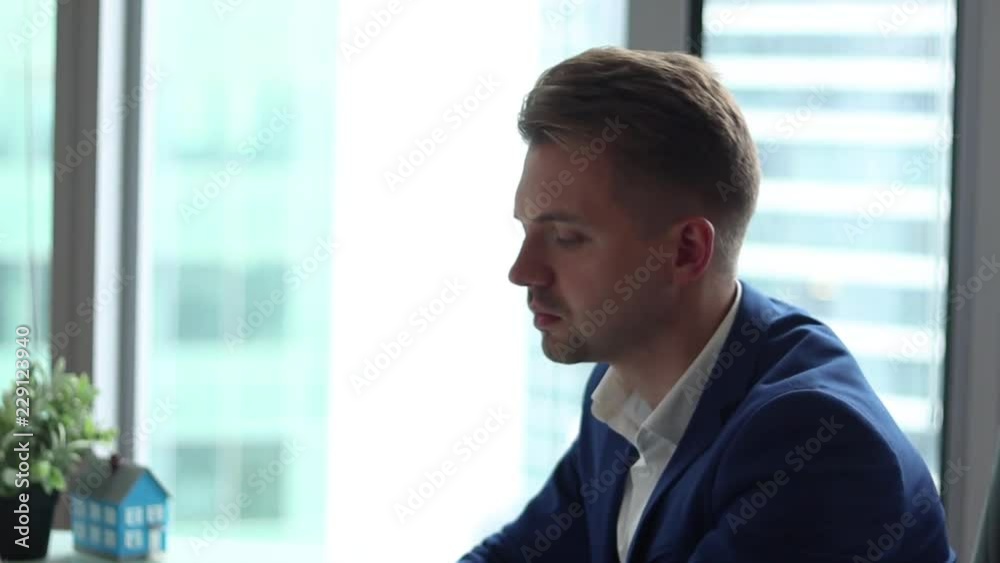 Young handsome businessman working at the computer sitting in his office.