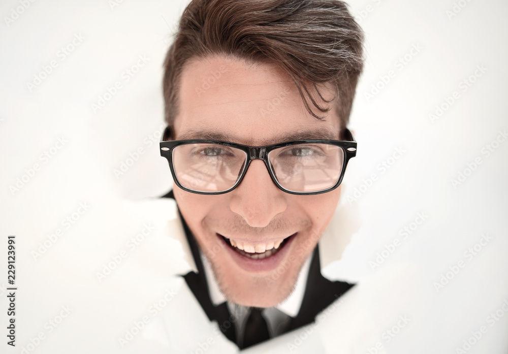 young businessman breaking through a white paper wall