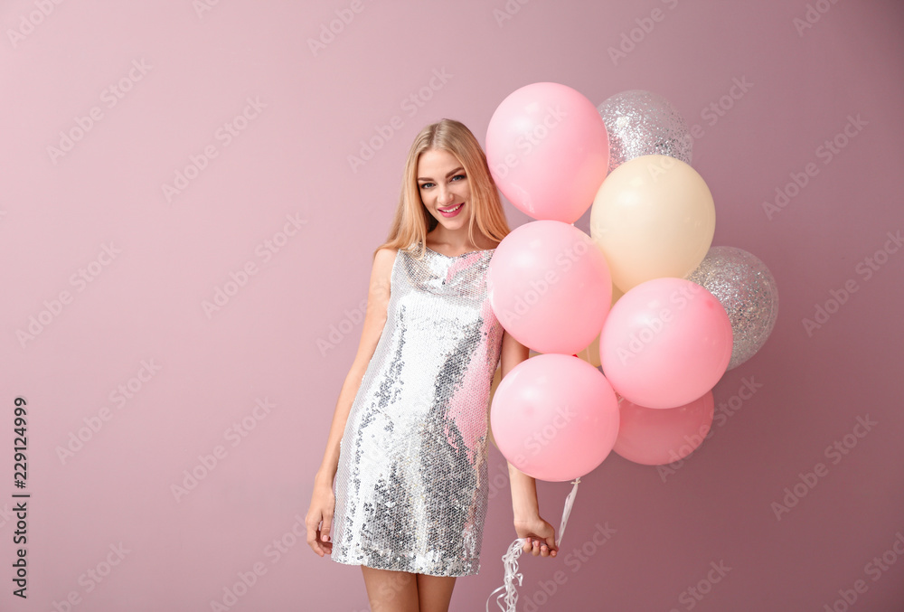 Beautiful young woman with air balloons on color background