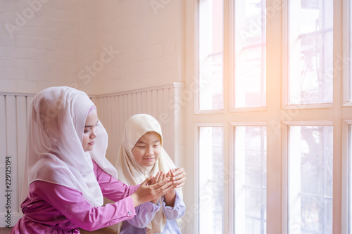 Happy family. Muslim asian woman mother teaching her daughter Duaa (praying to Allah) praying for God. photo