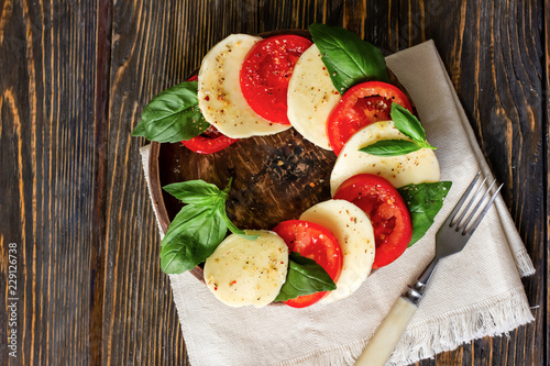 Caprese salad with mozzarella on a light wooden background, top view