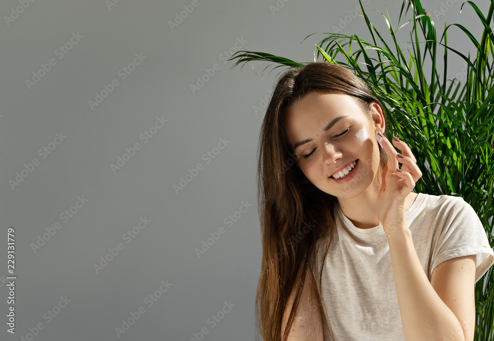 image of attractive girl applying cosmetic cream on her face image of attractive girl applying cosmetic cream on her face