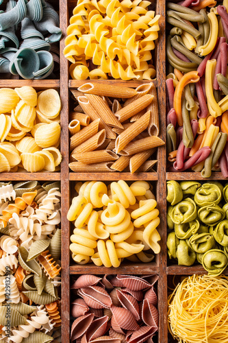 Assorted colorful italian pasta in wooden box. Healthy food background concept. Flat lay, top view.