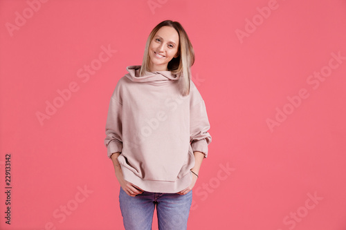 Сheerful young blond woman posing in pink pullover