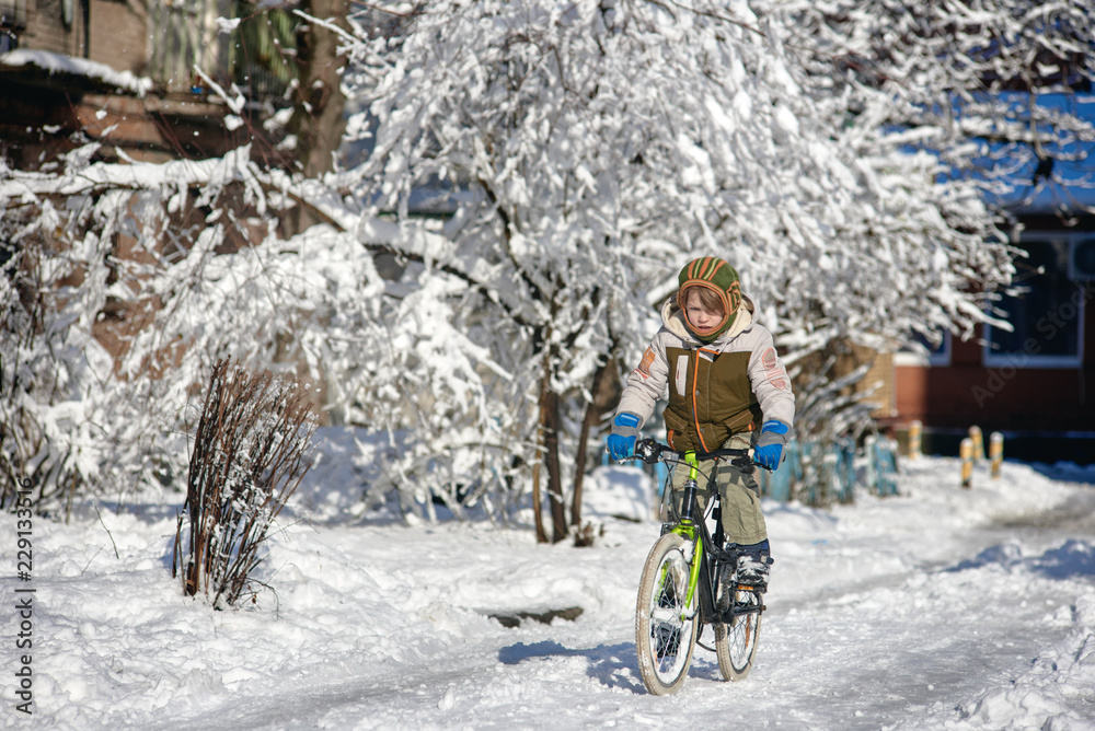 Naklejka premium Happy young guy riding bike on fresh snow