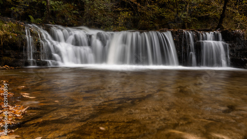 Waterfall Ddwli Isaf near pontneddfechan in the brecon beacons national park, Wales. It is autumn, and golden leaves are all around. Long shutter speed for a smooth effect on the water © parkerspics