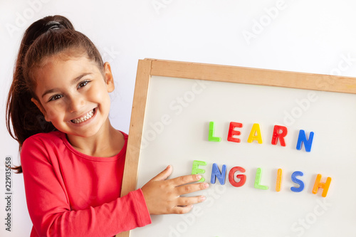 Language education concept. Learn English. Do you speak English. Cute little child girl with colored letters on the blackboard. English language school. English for children.