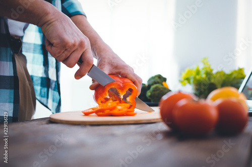 Equal slices. Close up of a nice handsome man cutting pepper into equal slices