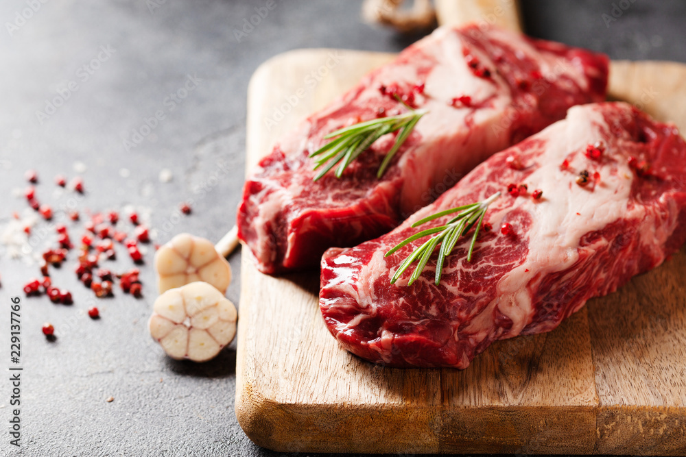 Raw Black Angus Prime meat steaks on wooden board copy space Raw Black Angus Prime meat steaks on wooden board copy space