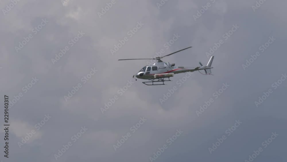 A rescue helicopter with stretcher flying in a cloudy sky A rescue helicopter with stretcher flying in a cloudy sky