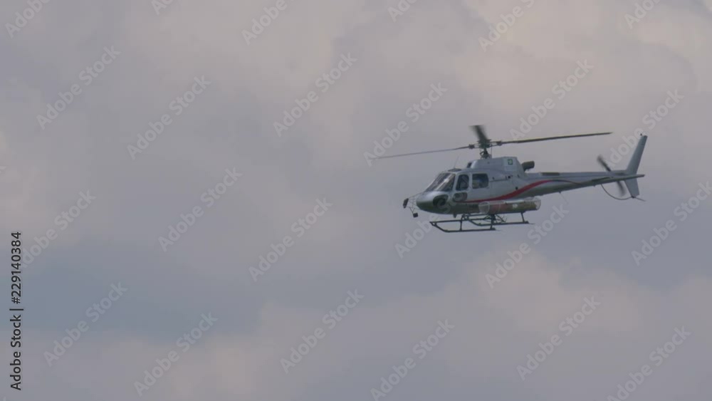 A rescue helicopter with stretcher flying in a cloudy sky A rescue helicopter with stretcher flying in a cloudy sky