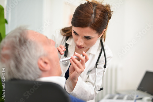 Doctor checking a patient's throat photo