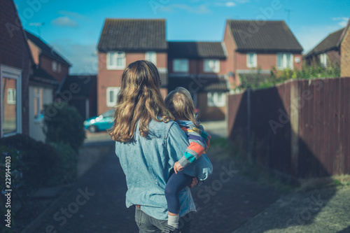 Photo Young mother holding her toddler in the suburbs