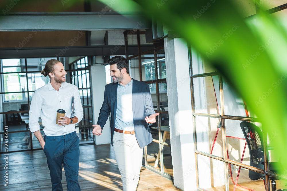 Fototapeta premium smiling business colleagues having conversation while walking in hall
