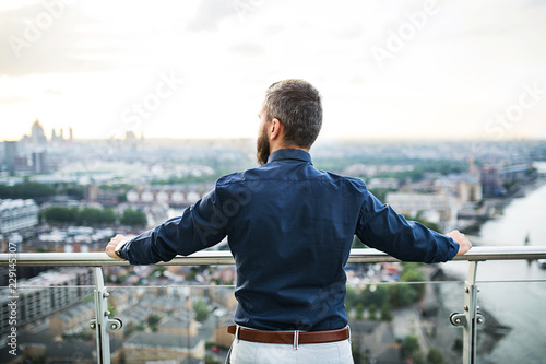 Canvas Print A rear view of businessman standing against London view panorama at sunset