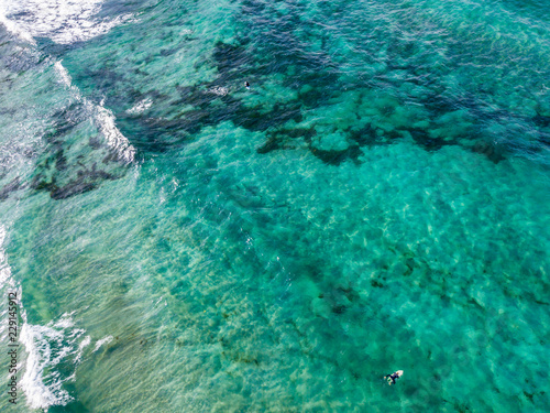 Vista aerea di un mare cristallino con onde e surfisti. Onde che si infrangono sulla spiaggia al tramonto, controluce. Playa De La Canteria. Oceano Atlantico. Orzola, Lanzarote, Isole Canarie. Spagna