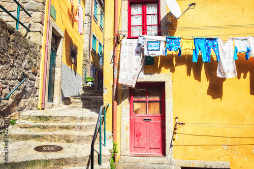 Fototapeta Naklejka Na Ścianę i Meble -  Colorful houses in a narrow street with hanging laundry, Ribeira district, Porto, Portugal.