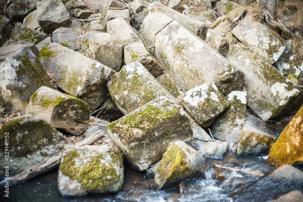 Broken rock on the bank of the stream. Amazing natural pentagonal blocks of stones. Nature reserve.