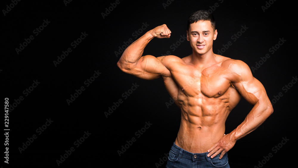 Fashionable masculinity. Handsome young man posing on a dark background. He is smiling and looks at camera. Fashionable masculinity. Handsome young man posing on a dark background. He is smiling and looks at camera.