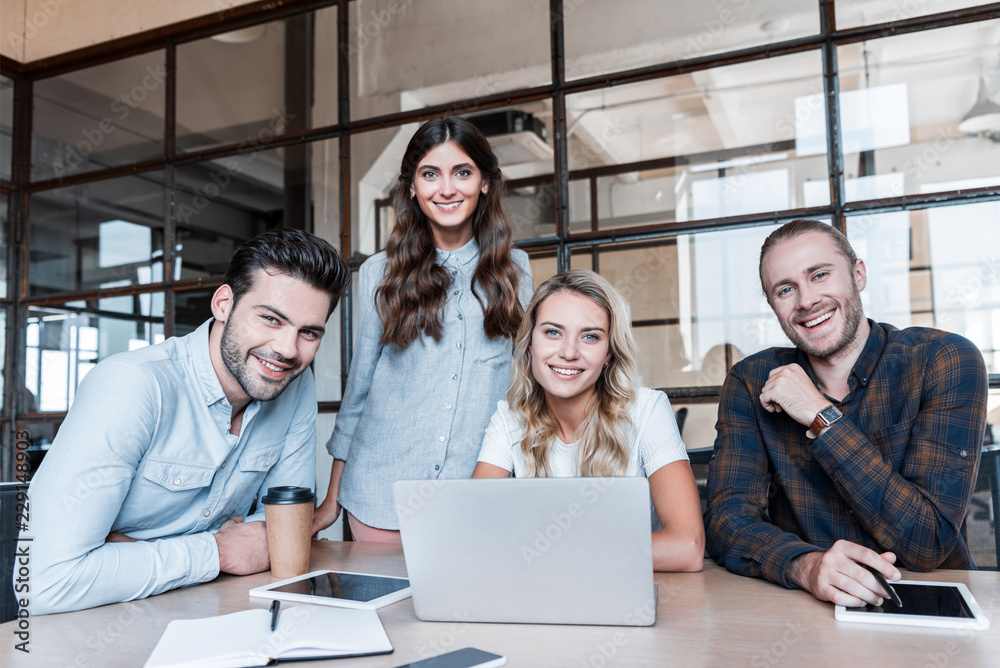 happy young business colleagues working with gadgets and smiling at camera in office happy young business colleagues working with gadgets and smiling at camera in office